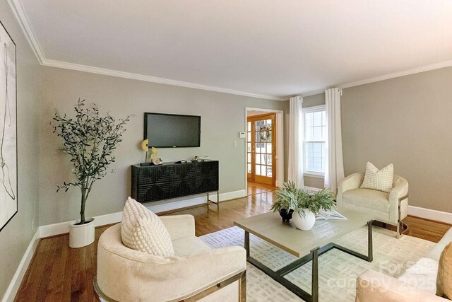 living area with baseboards, wood finished floors, and ornamental molding