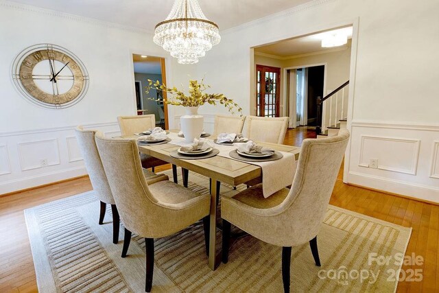 dining room with light wood finished floors, an inviting chandelier, and a decorative wall