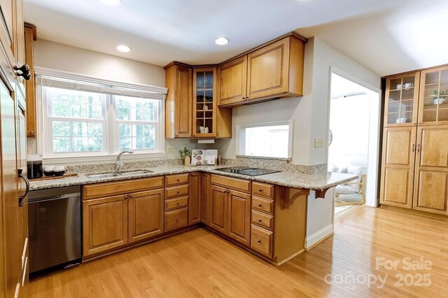 kitchen with light stone counters, dishwasher, brown cabinetry, a sink, and light wood-style flooring