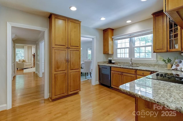 kitchen with light stone counters, a sink, light wood-style flooring, black dishwasher, and brown cabinetry