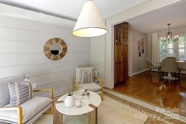 sitting room with baseboards, an inviting chandelier, and light wood-type flooring