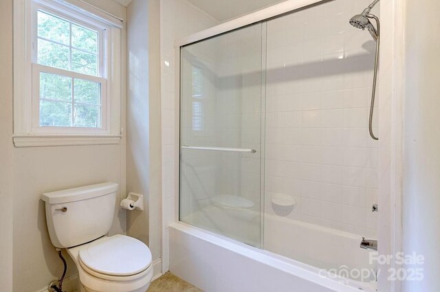 bathroom featuring enclosed tub / shower combo and toilet
