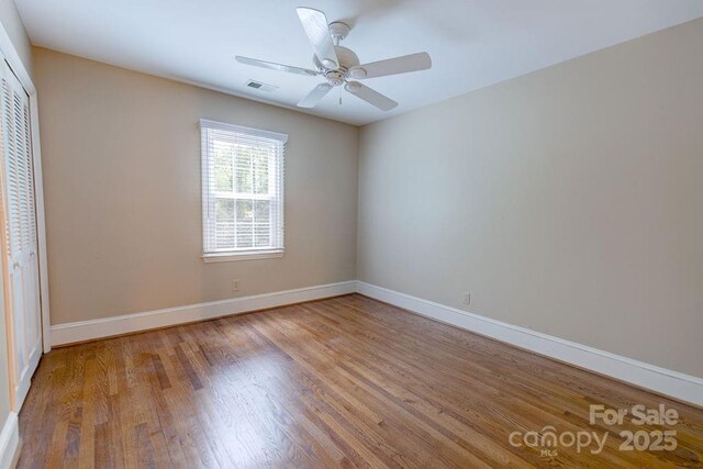 unfurnished bedroom with visible vents, baseboards, a ceiling fan, wood finished floors, and a closet