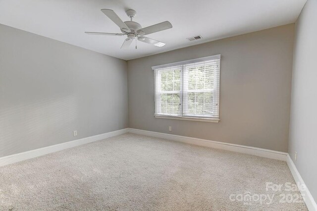 carpeted empty room featuring ceiling fan, baseboards, and visible vents