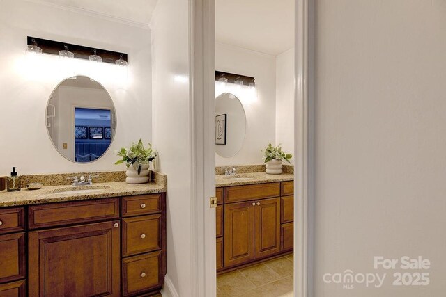 bathroom with two vanities, ornamental molding, and a sink