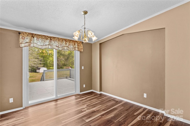 unfurnished dining area featuring a textured ceiling, baseboards, a chandelier, wood finished floors, and ornamental molding