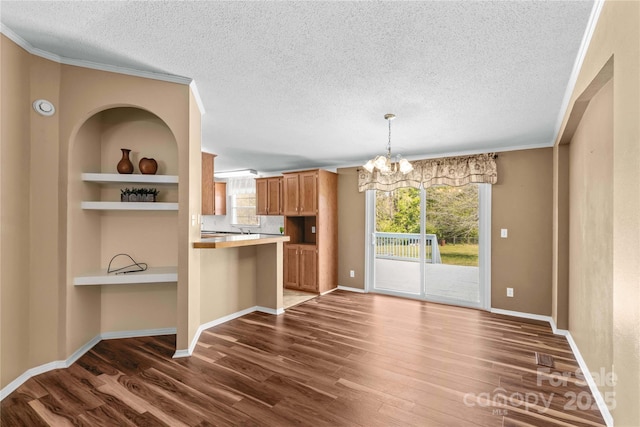 unfurnished dining area with an inviting chandelier, a textured ceiling, dark wood-type flooring, and plenty of natural light