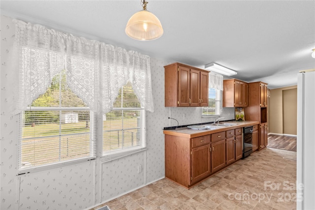 kitchen with wallpapered walls, brown cabinetry, pendant lighting, light countertops, and baseboards