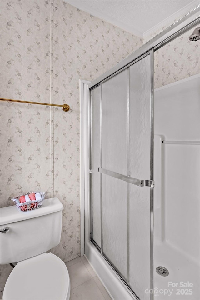 bathroom featuring wallpapered walls, toilet, a stall shower, and crown molding