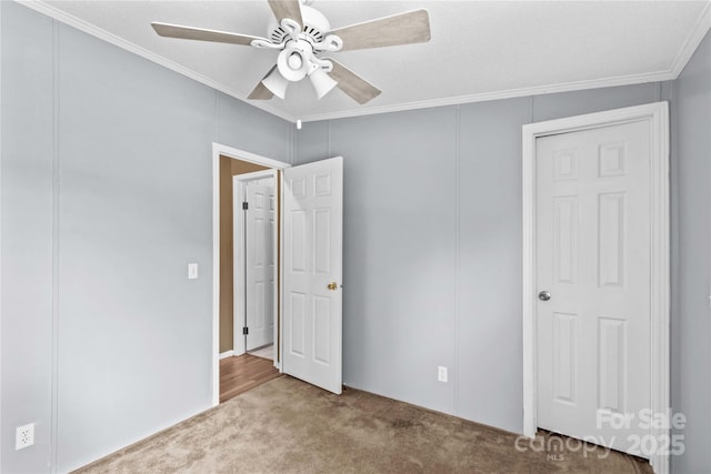 unfurnished bedroom with ceiling fan, crown molding, and carpet flooring