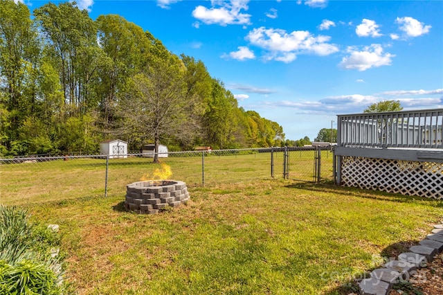 view of yard with fence, a fire pit, a gate, and a deck