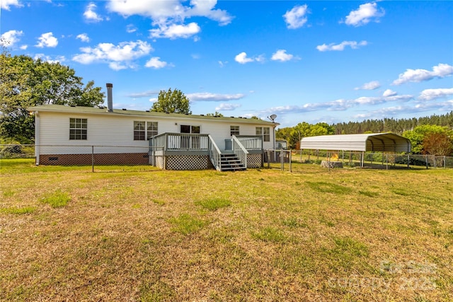 rear view of house featuring a carport, a wooden deck, a lawn, and fence
