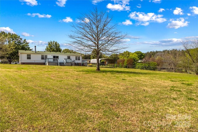 view of yard with a wooden deck, fence, and a carport