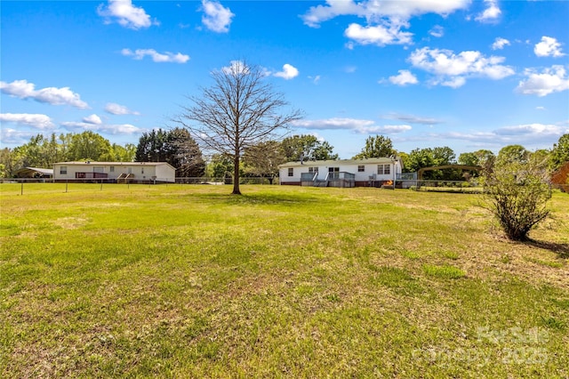 view of yard with a detached carport, a fenced backyard, and a deck