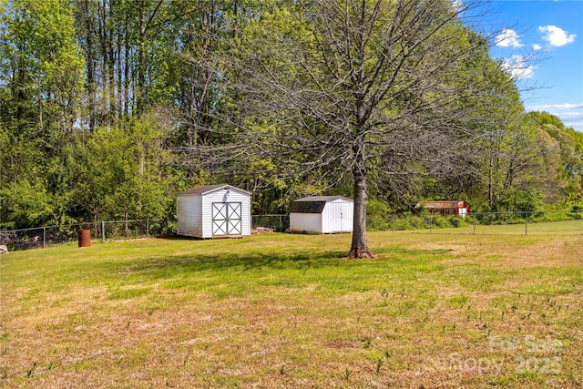 view of yard featuring fence, a storage unit, and an outbuilding