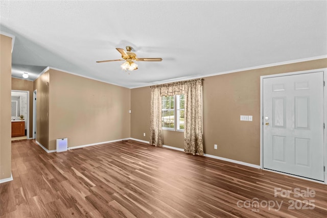 unfurnished living room with crown molding, a ceiling fan, and baseboards