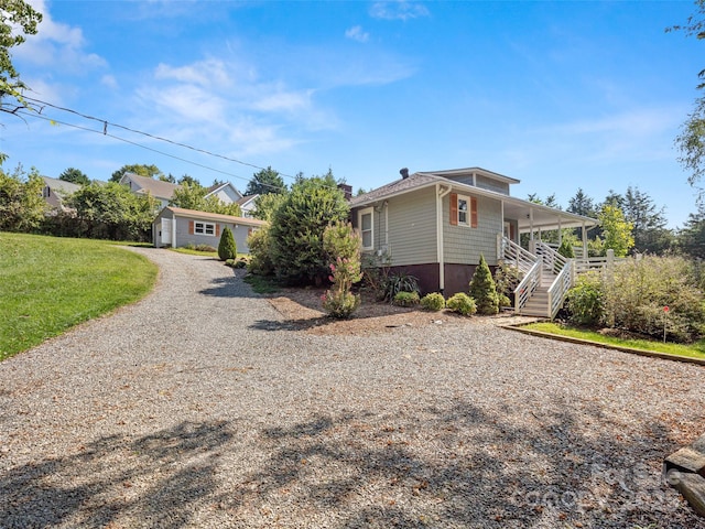 view of front of property with a front lawn, stairway, covered porch, driveway, and a chimney