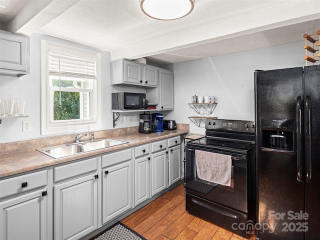 kitchen featuring black appliances, light countertops, light wood finished floors, and a sink