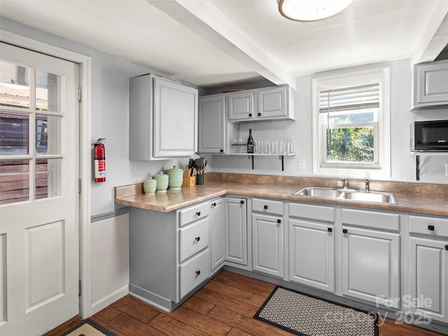 kitchen featuring gray cabinets, a sink, open shelves, and dark wood finished floors