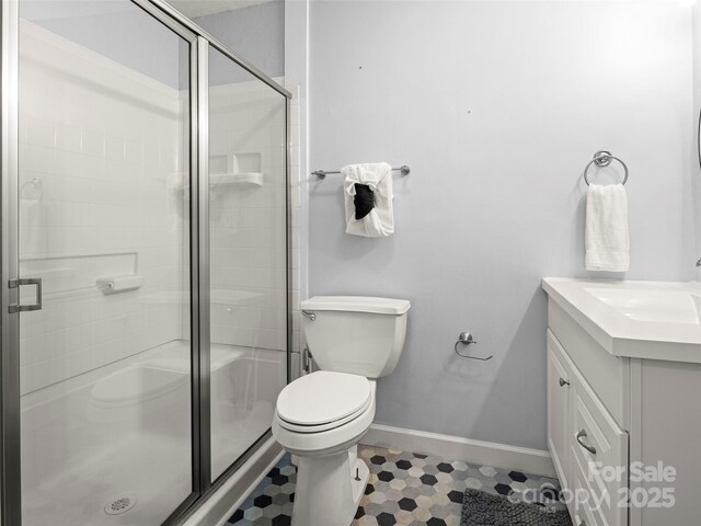 full bath with vanity, toilet, a stall shower, and baseboards