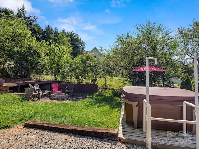 view of yard with a hot tub and an outdoor fire pit
