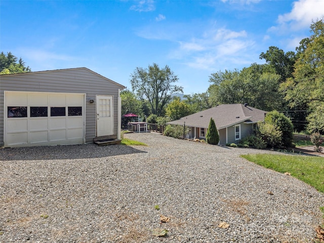 exterior space featuring driveway, a garage, and an outbuilding