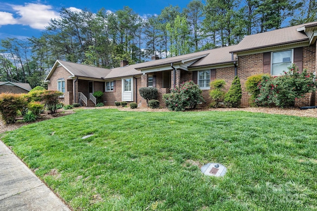 ranch-style home with brick siding, a front lawn, and a chimney
