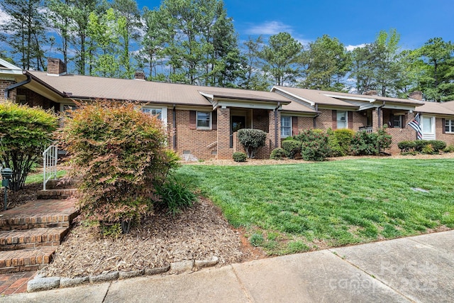 single story home featuring brick siding, a front lawn, and a chimney