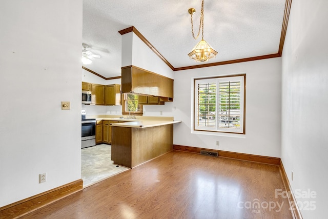 kitchen with crown molding, light wood-style floors, appliances with stainless steel finishes, and vaulted ceiling