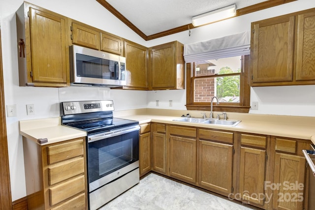 kitchen with stainless steel appliances, light countertops, a sink, and ornamental molding