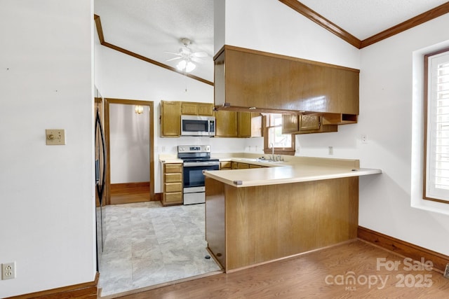 kitchen with a peninsula, a sink, vaulted ceiling, and appliances with stainless steel finishes