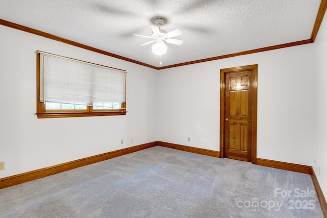empty room with baseboards, ornamental molding, a ceiling fan, a textured ceiling, and carpet flooring