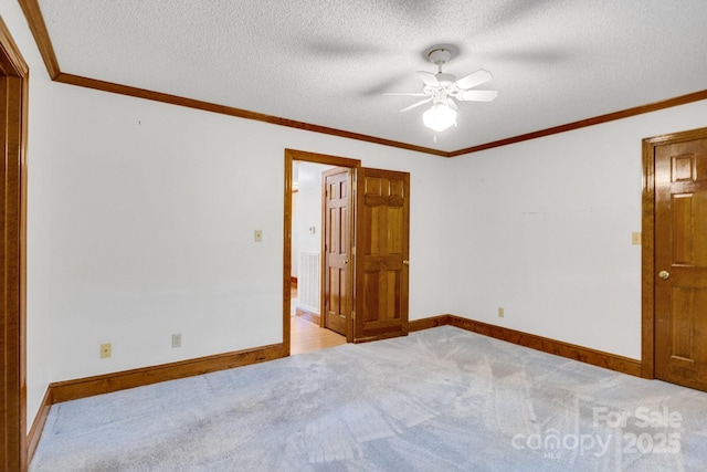 spare room with baseboards, ornamental molding, a textured ceiling, a ceiling fan, and carpet