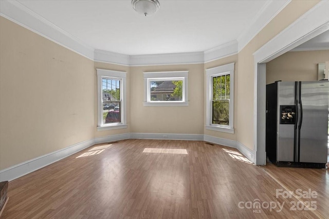 unfurnished room with baseboards, ornamental molding, and wood finished floors