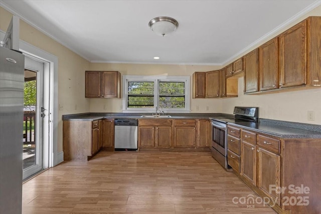 kitchen featuring dark countertops, light wood-style flooring, appliances with stainless steel finishes, and brown cabinetry