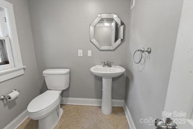 half bathroom featuring baseboards, tile patterned flooring, and toilet