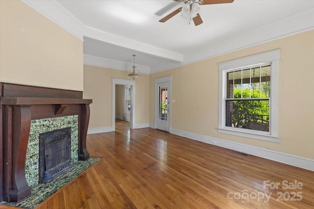 unfurnished living room with baseboards, visible vents, a ceiling fan, wood finished floors, and a fireplace