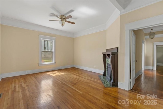 unfurnished living room featuring baseboards, ornamental molding, ceiling fan, a high end fireplace, and wood-type flooring