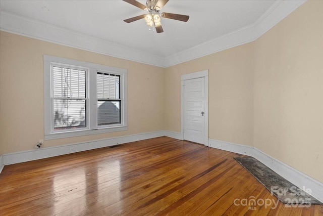 spare room with baseboards, visible vents, a ceiling fan, hardwood / wood-style floors, and ornamental molding