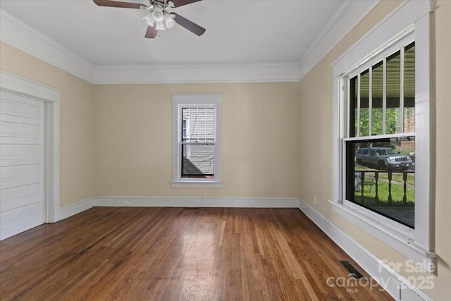 empty room featuring wood finished floors, visible vents, ornamental molding, and plenty of natural light