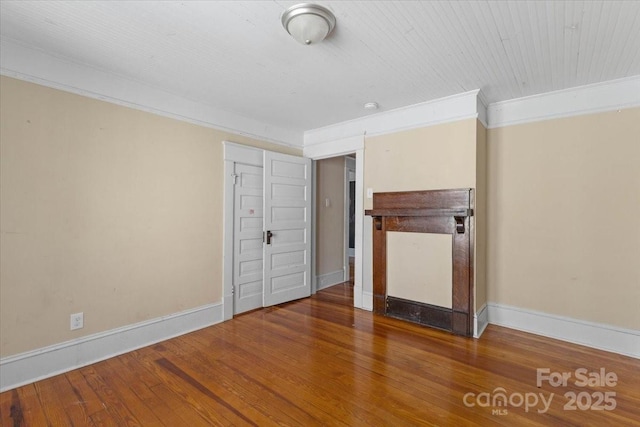 unfurnished bedroom featuring wood finished floors, baseboards, and ornamental molding