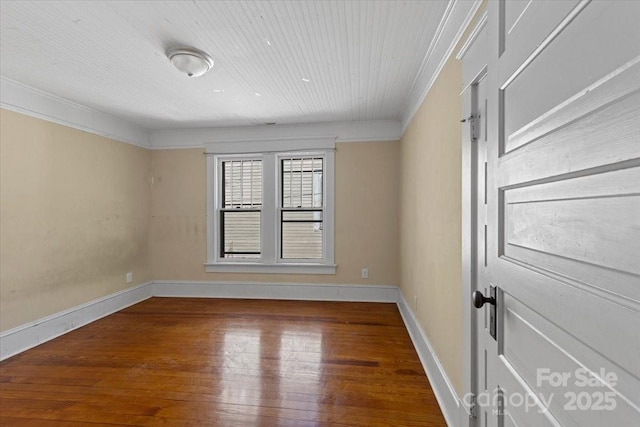 empty room with wood-type flooring, baseboards, and ornamental molding