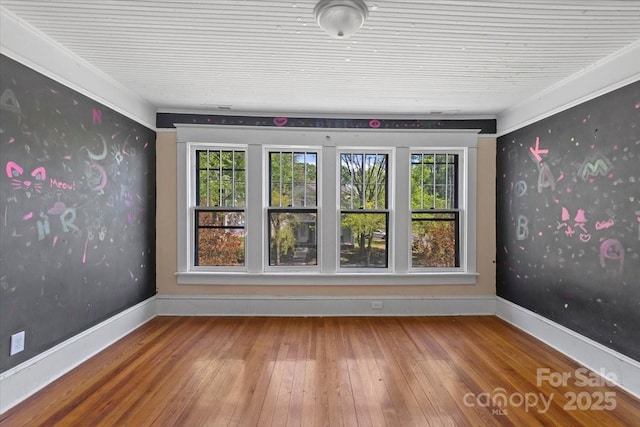 spare room featuring hardwood / wood-style flooring and baseboards