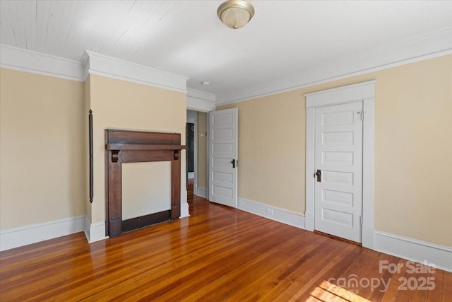 unfurnished living room featuring baseboards, ornamental molding, and wood finished floors