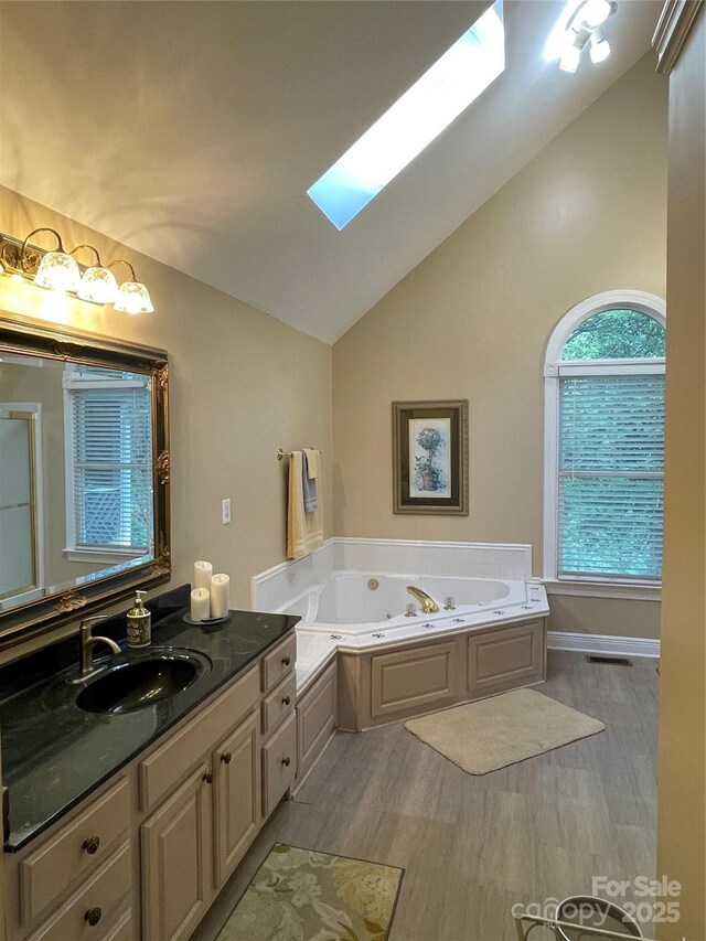 121 General Pemberton St, Stanley, NC 28164 - bathroom featuring vaulted ceiling with skylight, vanity, a tub with jets, visible vents, and wood finished floors