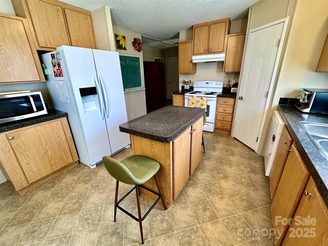 2084 Bristol Creek Ave, Morganton, NC 28655 - kitchen featuring dark countertops, white appliances, a center island, a kitchen bar, and under cabinet range hood