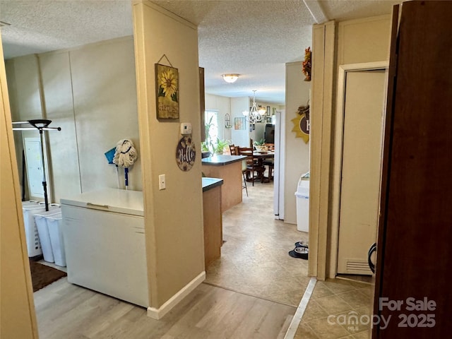 2084 Bristol Creek Ave, Morganton, NC 28655 - hall featuring light wood-style floors, a textured ceiling, and a notable chandelier