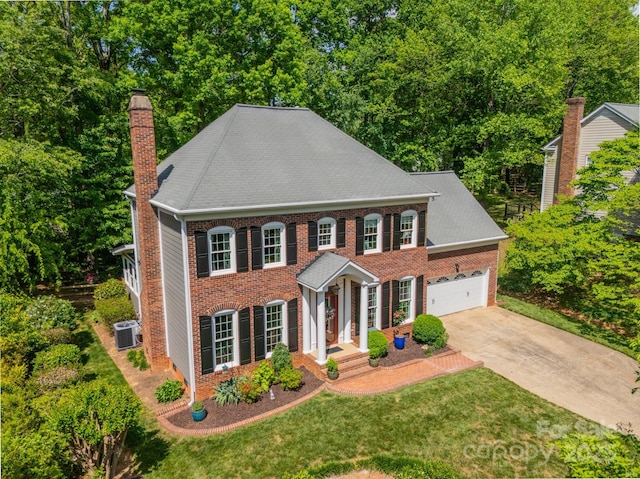 view of front of house featuring a chimney, brick siding, driveway, central AC, and a front lawn