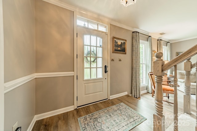 foyer featuring stairway, wood finished floors, crown molding, and baseboards