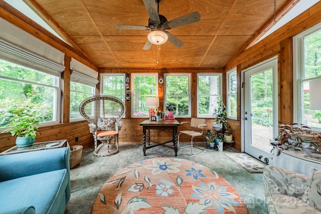 sunroom featuring wood walls, a healthy amount of sunlight, and lofted ceiling
